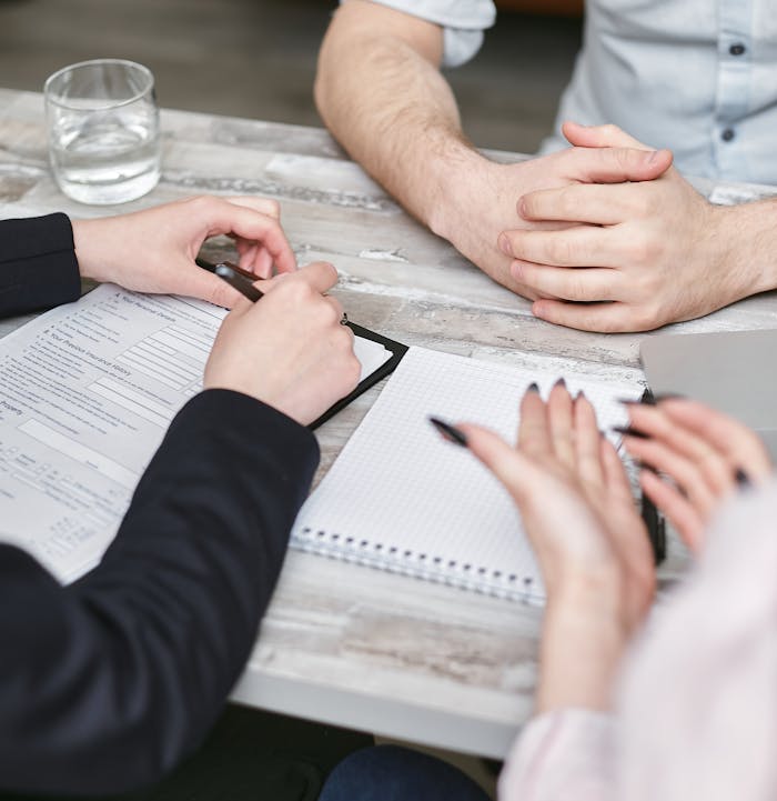 Close-up view of a team meeting with documents and notebooks on a wooden desk.